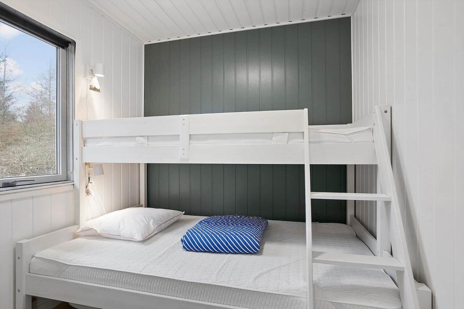 Room with bunk bed, window, and wall lighting.