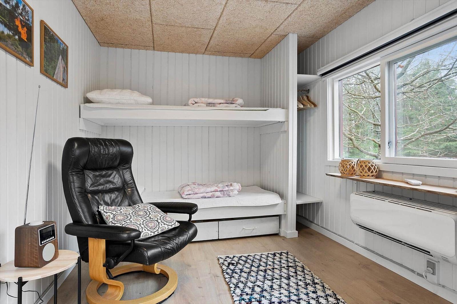 Bedroom with bunk bed, black leather chair, and window view of forest.