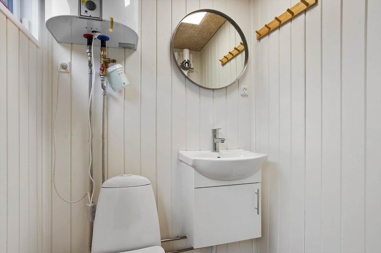 Bathroom with toilet, sink, and mirror on white panels.