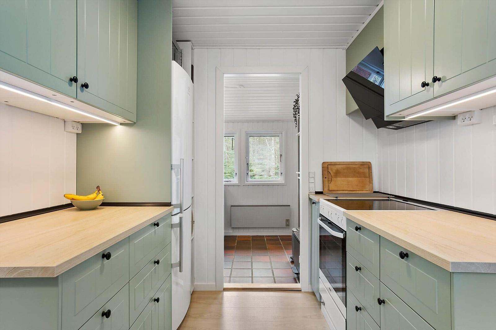 Kitchen with light cabinets, wooden countertops, and view into living area.