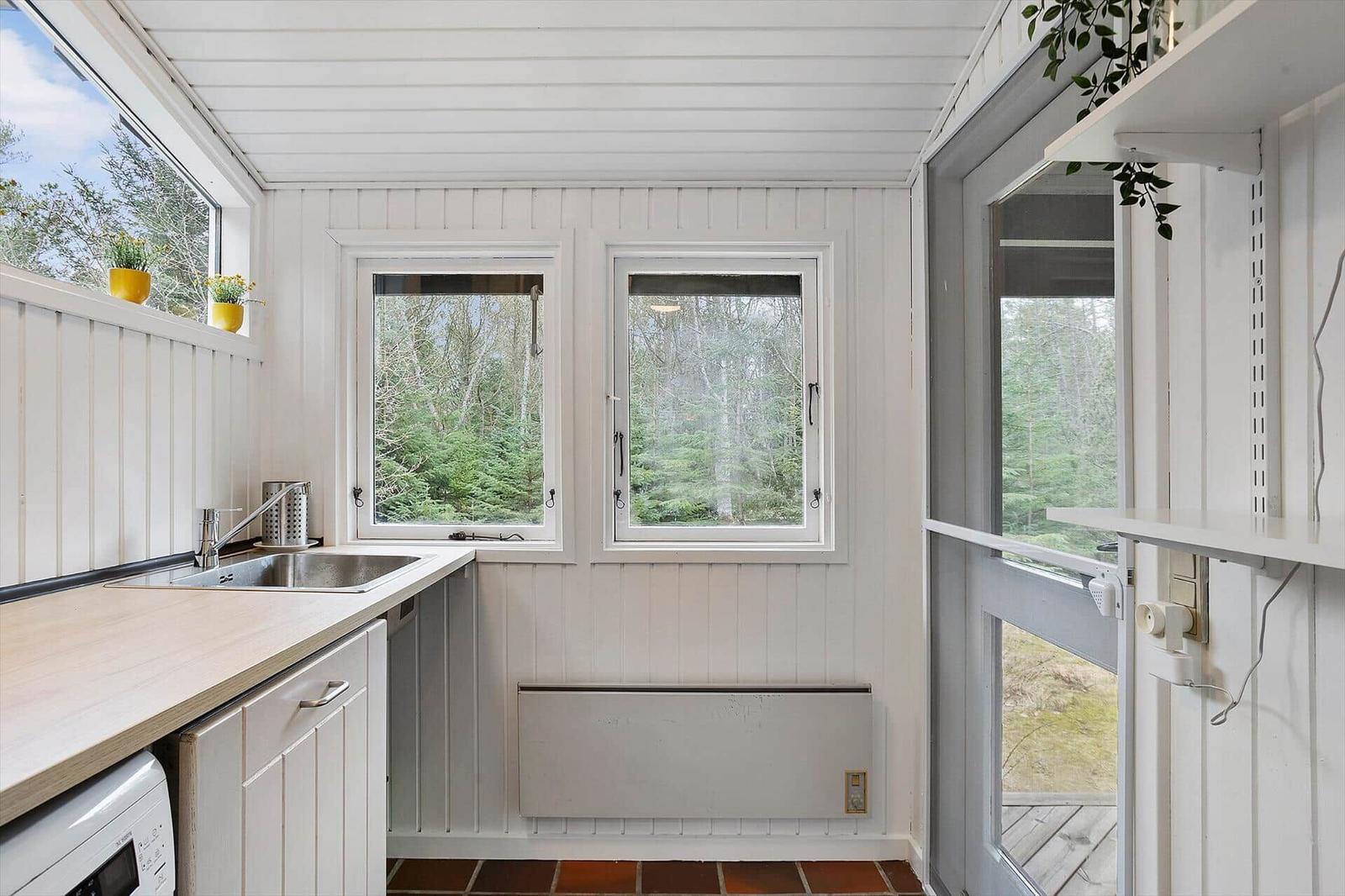 Kitchen with windows, worktop, and view of the forest.