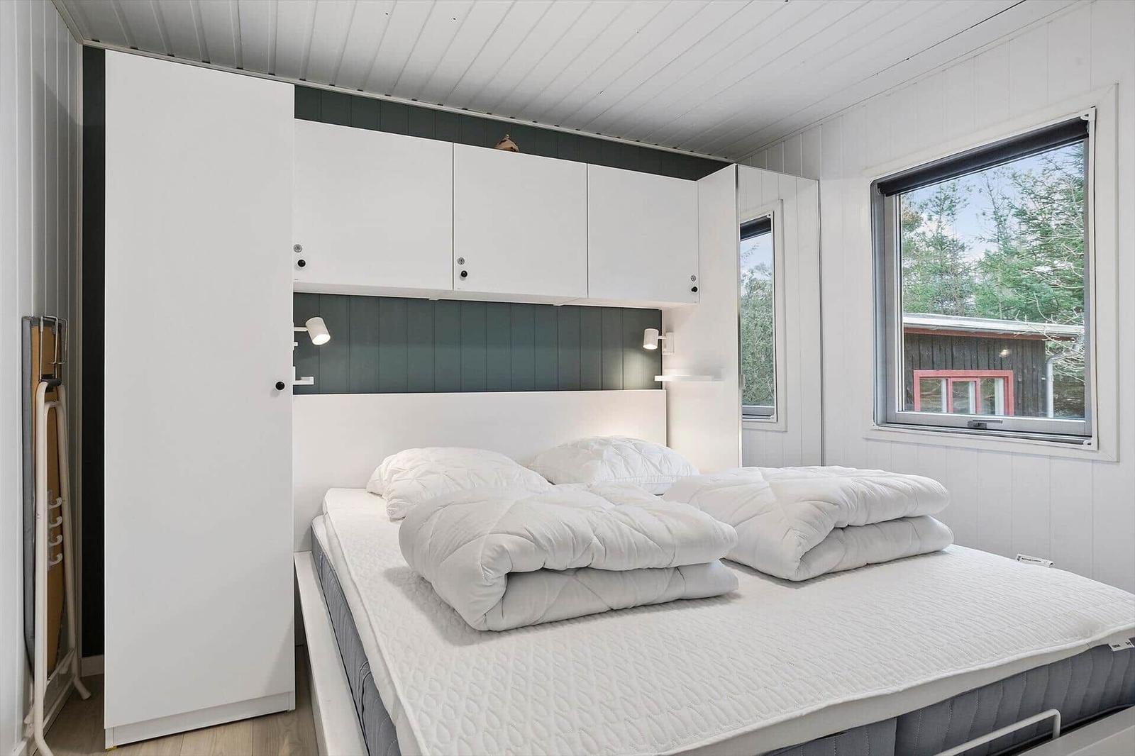 Bedroom with white bed, closet, and window to the outdoors.