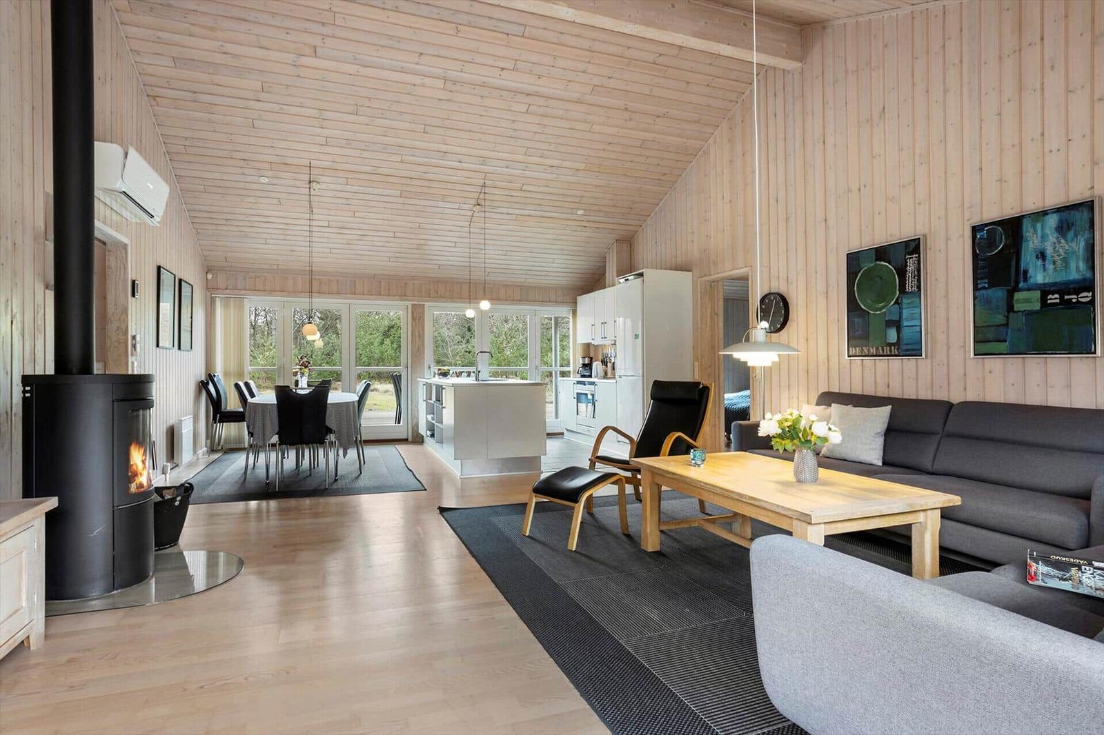 Living and dining area with wood paneling, fireplace, and modern kitchen.