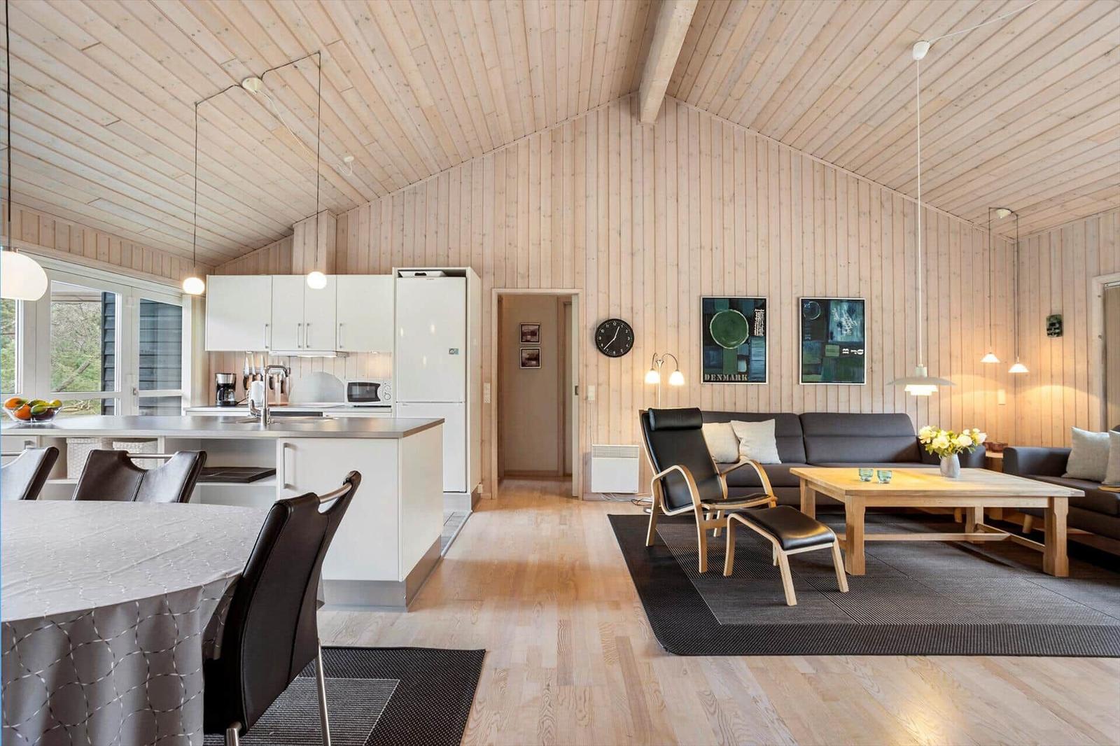 Modern kitchen with dining area and living room with sofa and dining table.