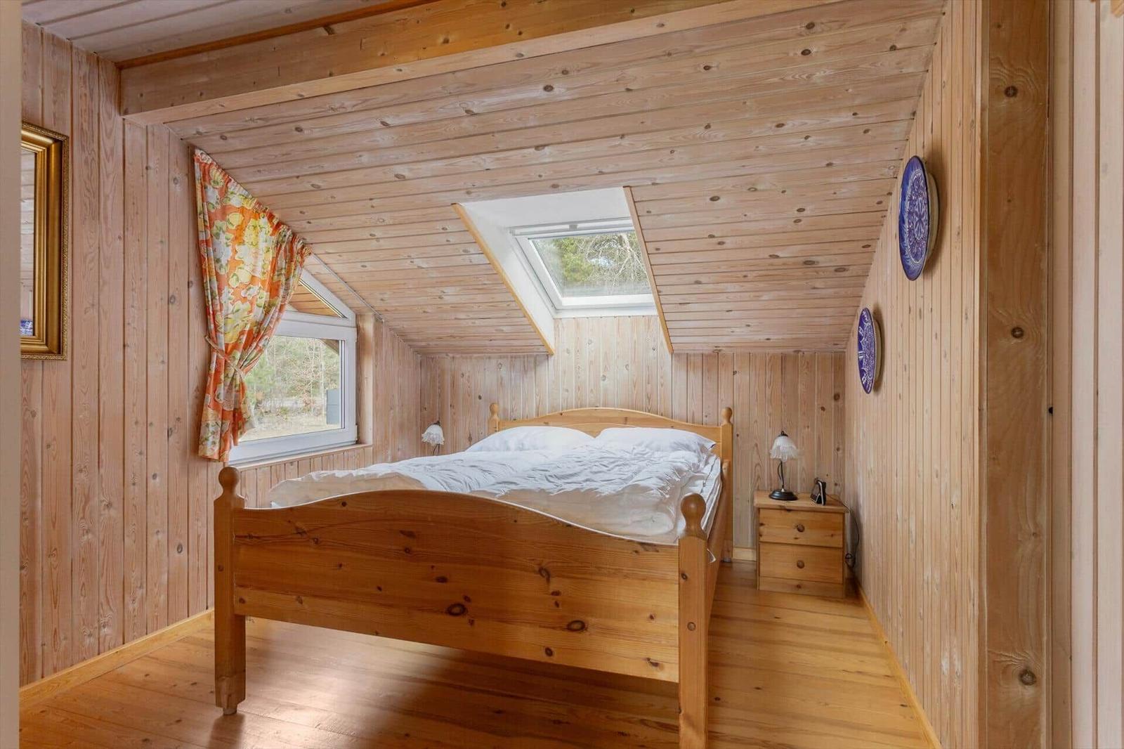 Bedroom with wooden walls, bed, window, and skylight.