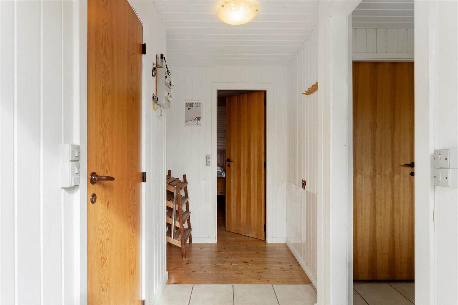 Hallway with wooden doors and white walls. Wooden floor and ceiling.