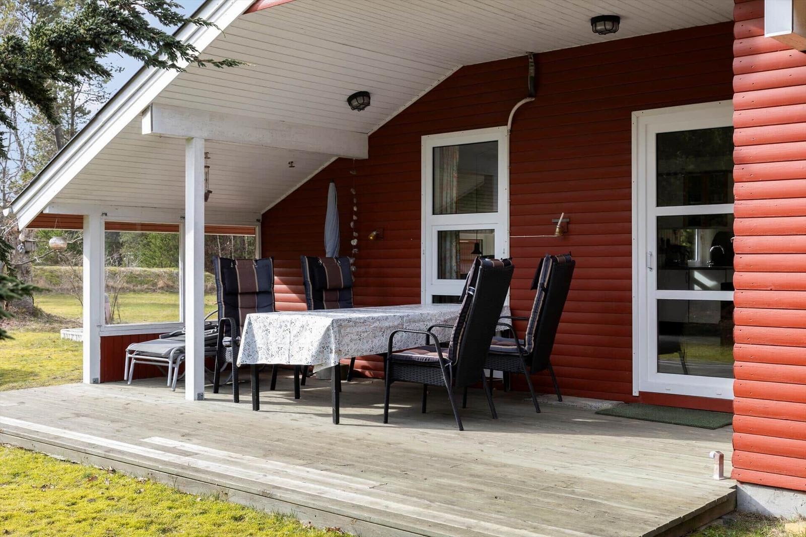 Patio with table and chairs in front of red wooden house