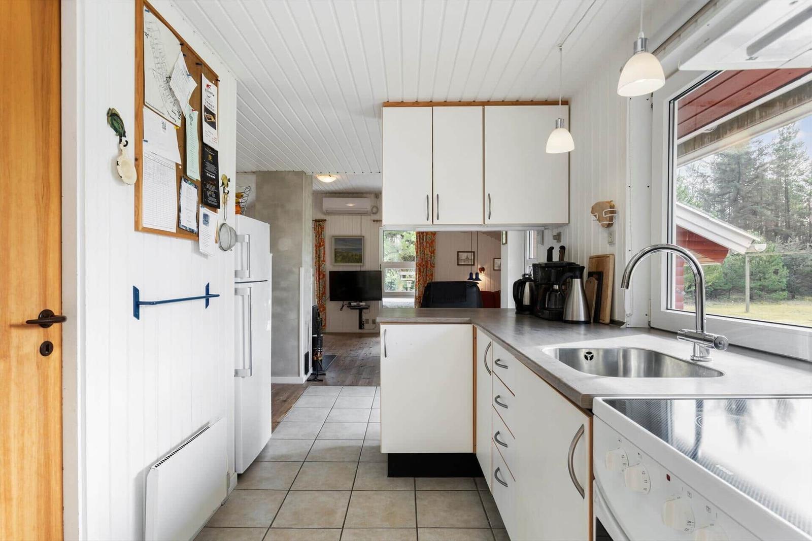 Kitchen with white countertop, sink, and window view of forest.