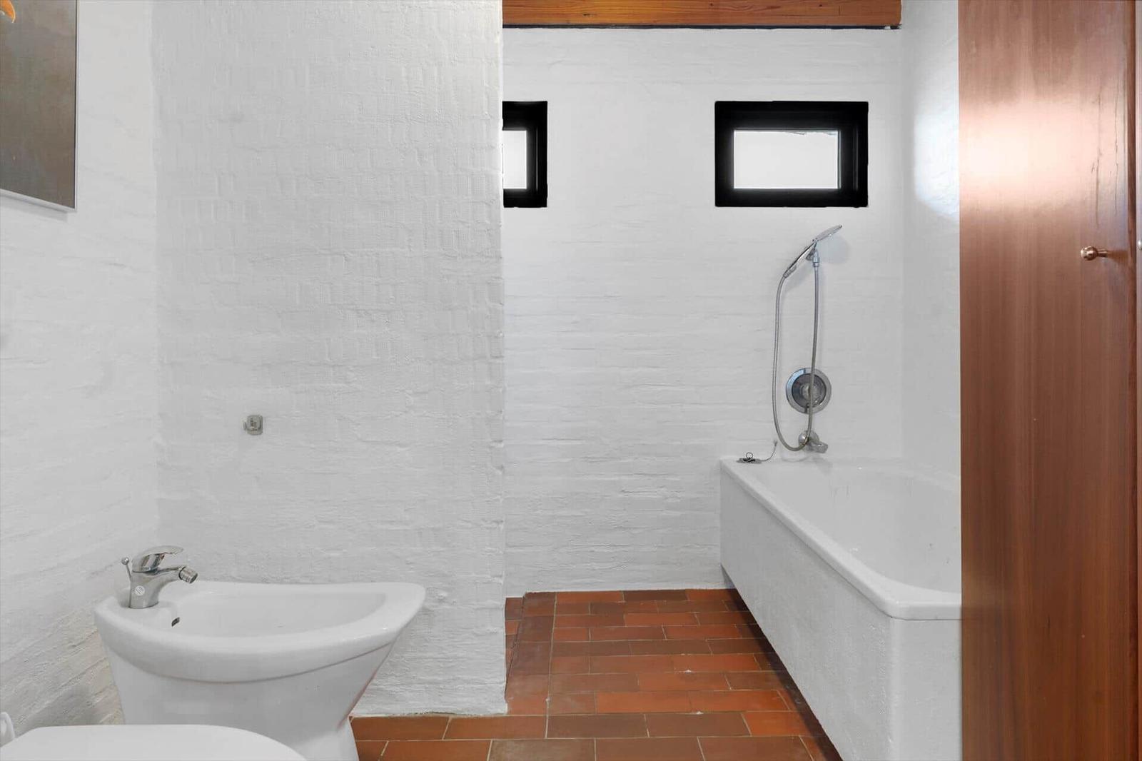 Badezimmer mit Badewanne, Bidet und zwei Fenstern