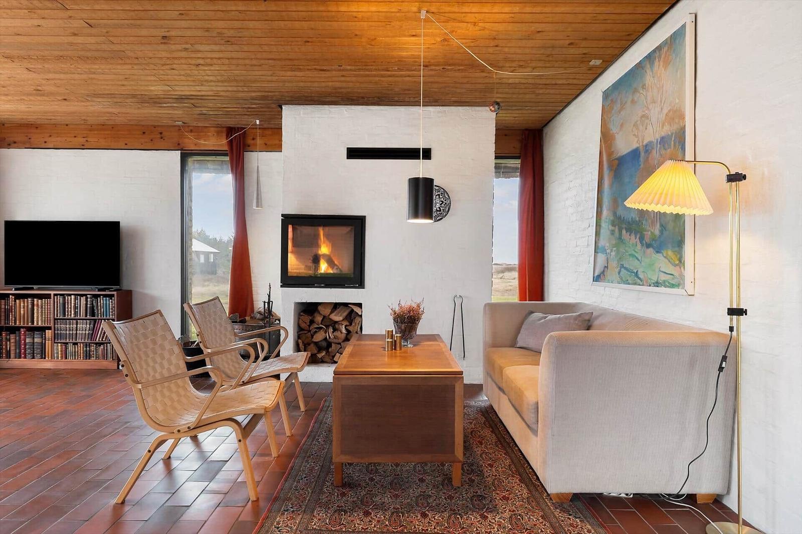 Wohnzimmer mit Kamin, Sofa, zwei Stühlen und Fernseher an der Wand.