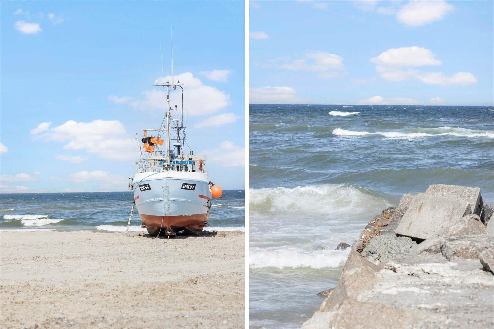 Fischerboot HM94 am Strand. Wellen brechen an Steinen.