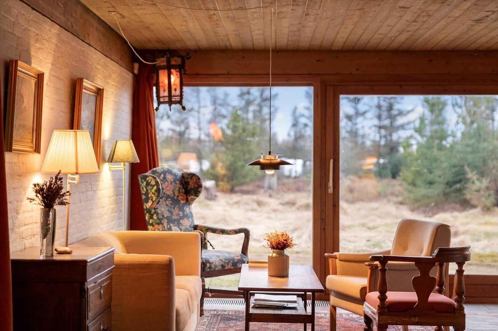 Ein Wohnzimmer mit Sitzgelegenheiten und Blick auf einen Wald.