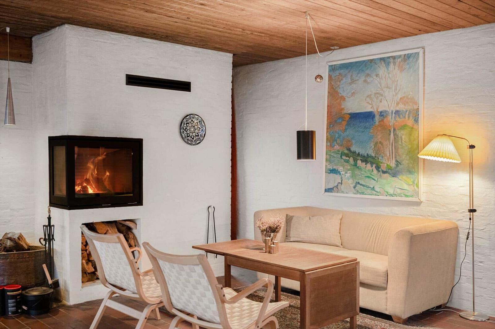 Wohnzimmer mit Kamin, Sofa, Tisch und Wandbild.