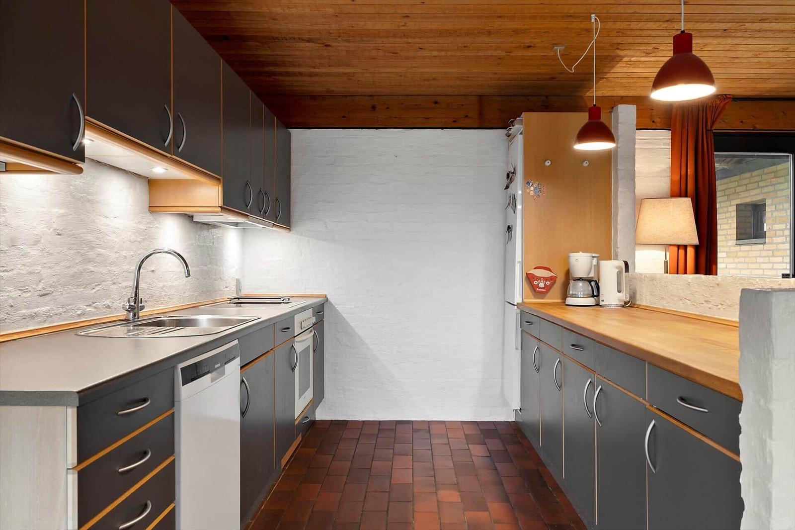 Küche mit Holzdecke, Arbeitsplatten und Küchengeräten.