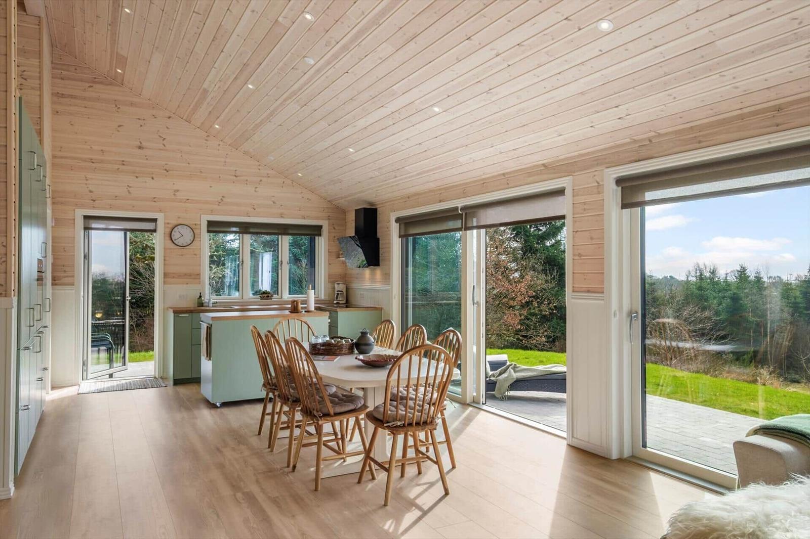 Entrance area with dining space, kitchen, and view of garden and forest.