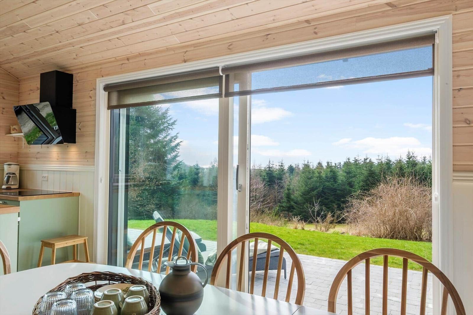 Dining area with view of lawn and forest through sliding door.