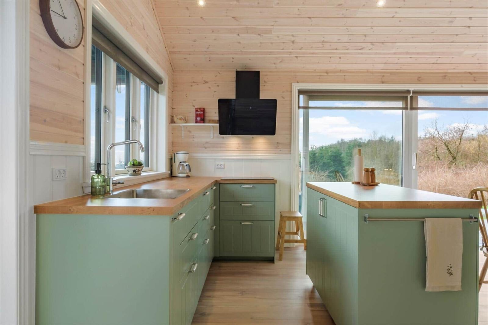 Kitchen with green cabinets, wooden surfaces, and view of the landscape.