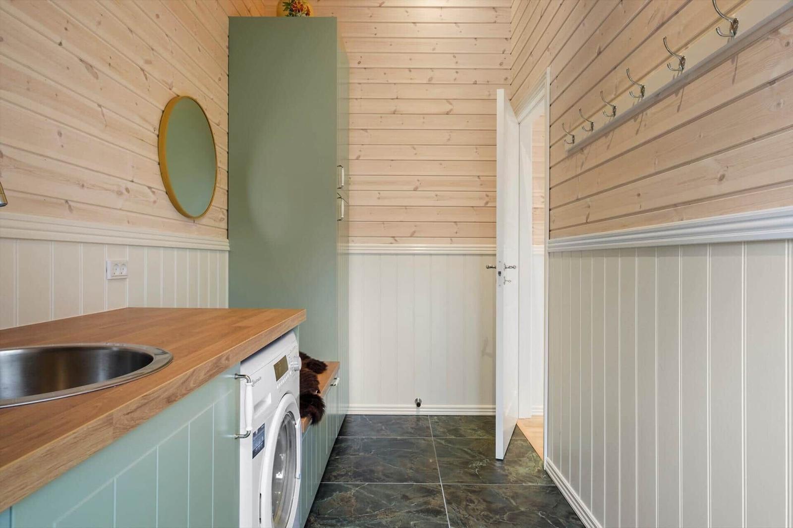 Laundry room with washing machine, wood wall, and hook row