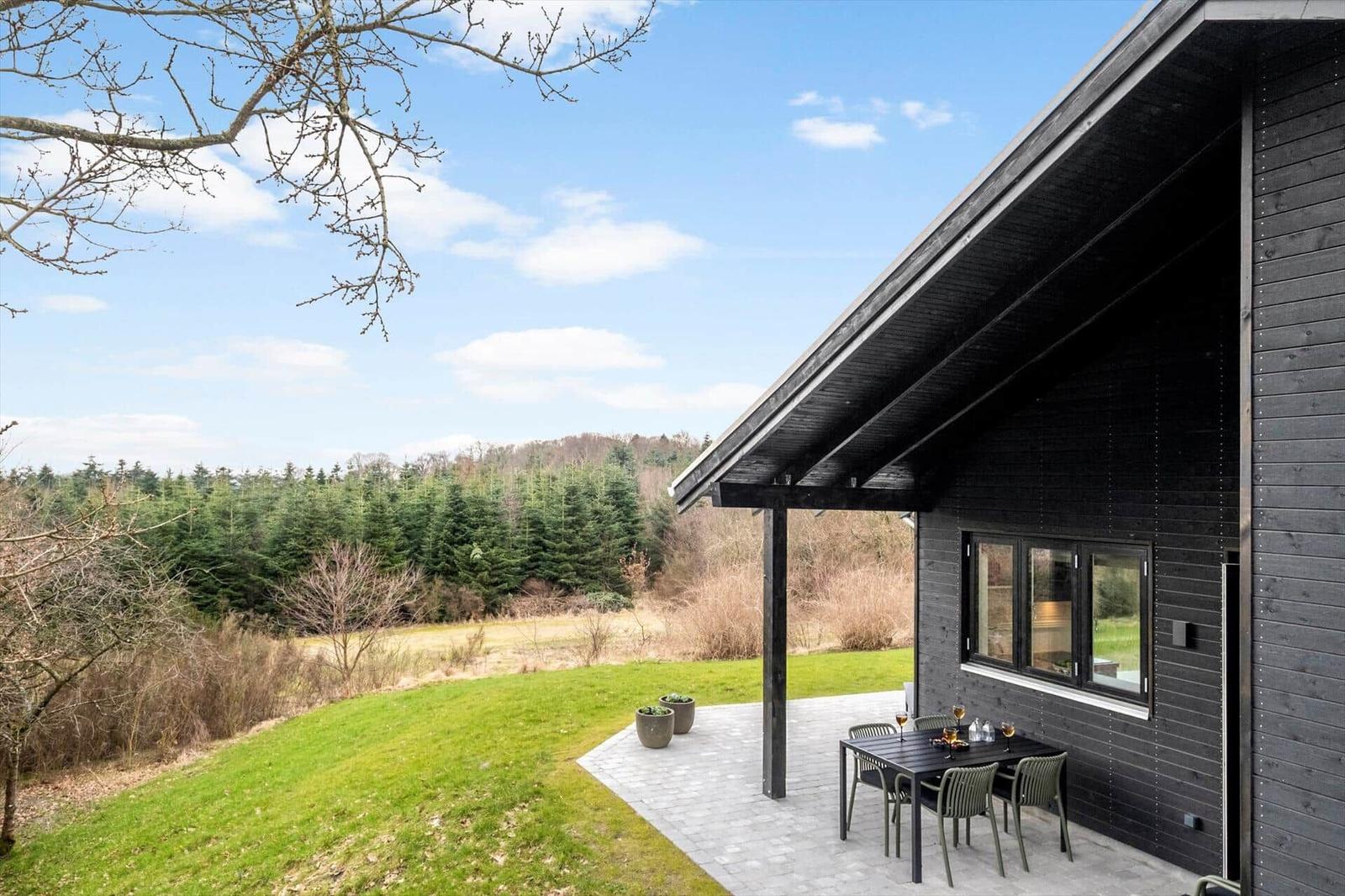Modern house with terrace, garden, and forest view.