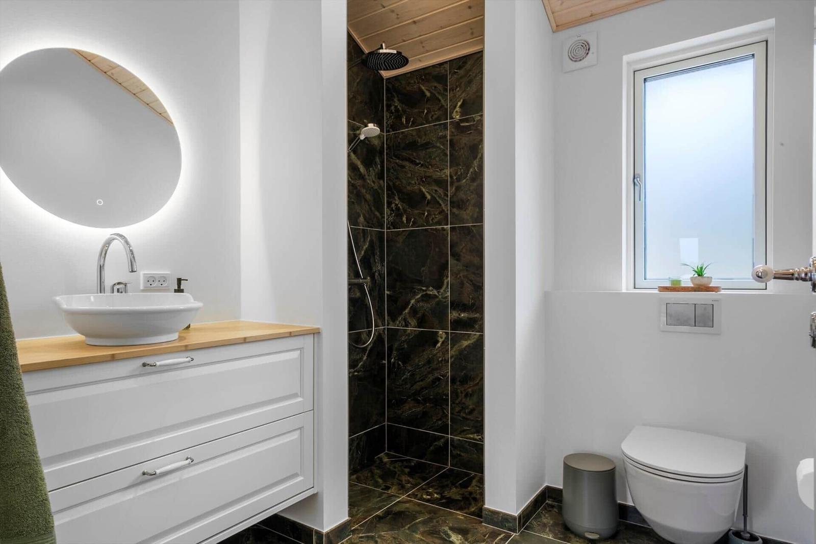 Bathroom with shower, sink, and toilet. Wood and marble look.