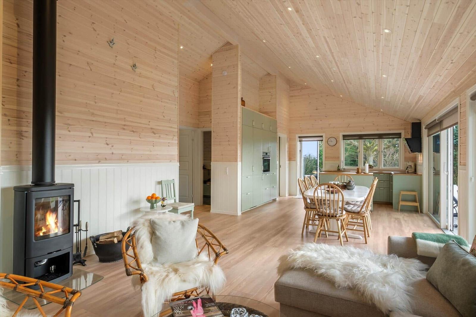 Living and dining area with fireplace, wooden ceiling, and dining set.