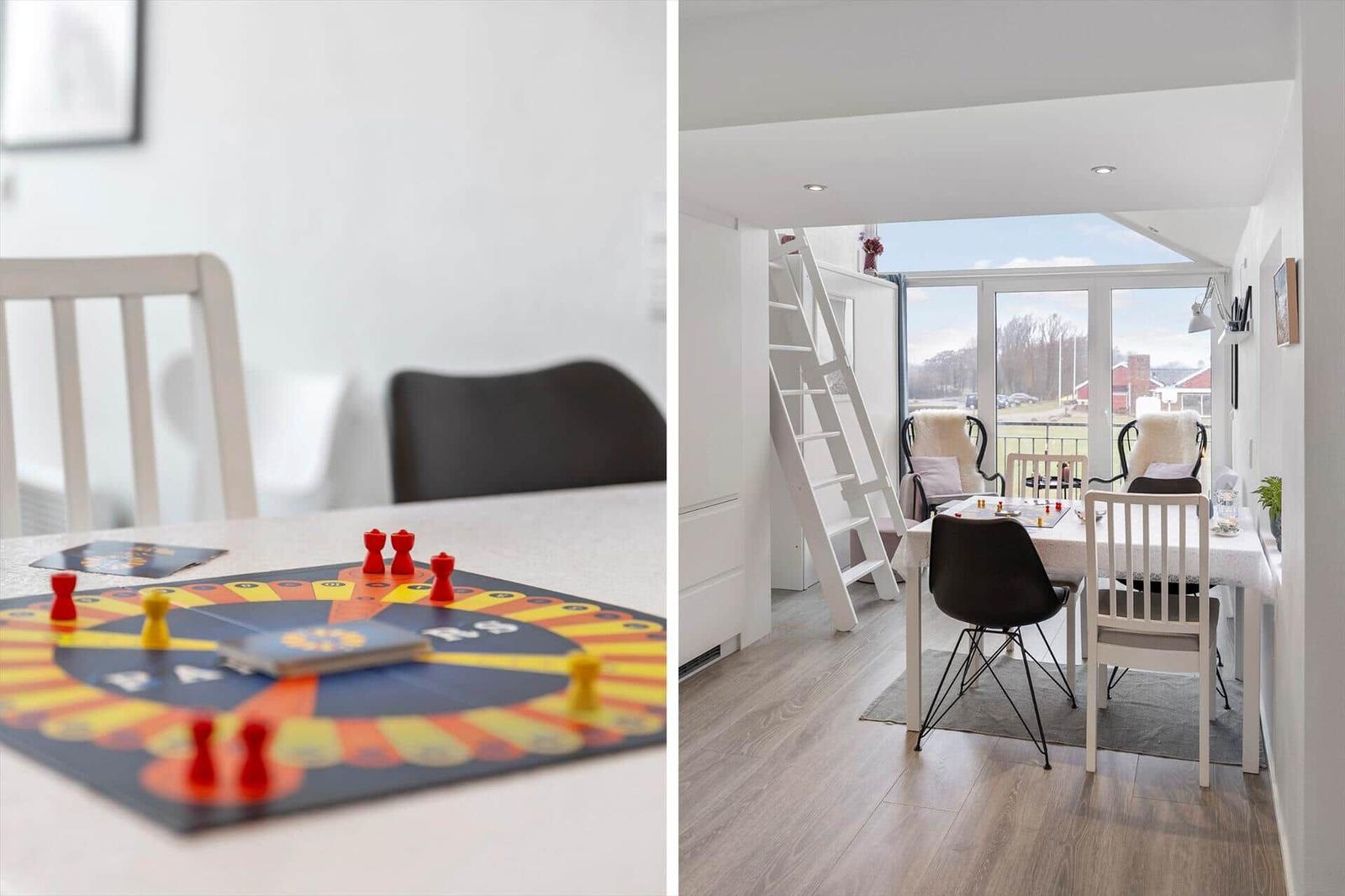 Tisch mit Spiel und Sitzgelegenheiten in einem hellen Raum mit Fenster und Leiter.