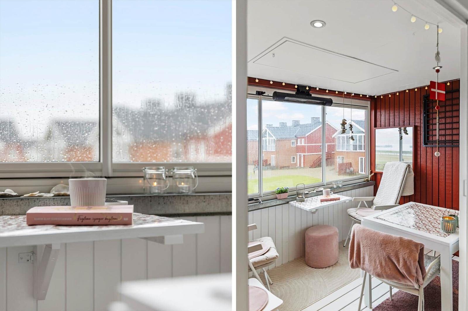 Terrasse mit Tisch, Stühlen und Blick auf rote Häuser. Fenster mit Regentropfen und dampfender Tasse.