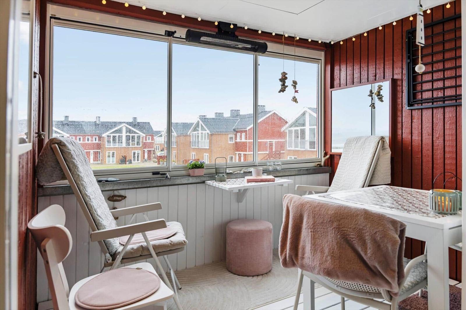 Terrasse mit Sitzgelegenheiten und Blick auf rote Häuser.