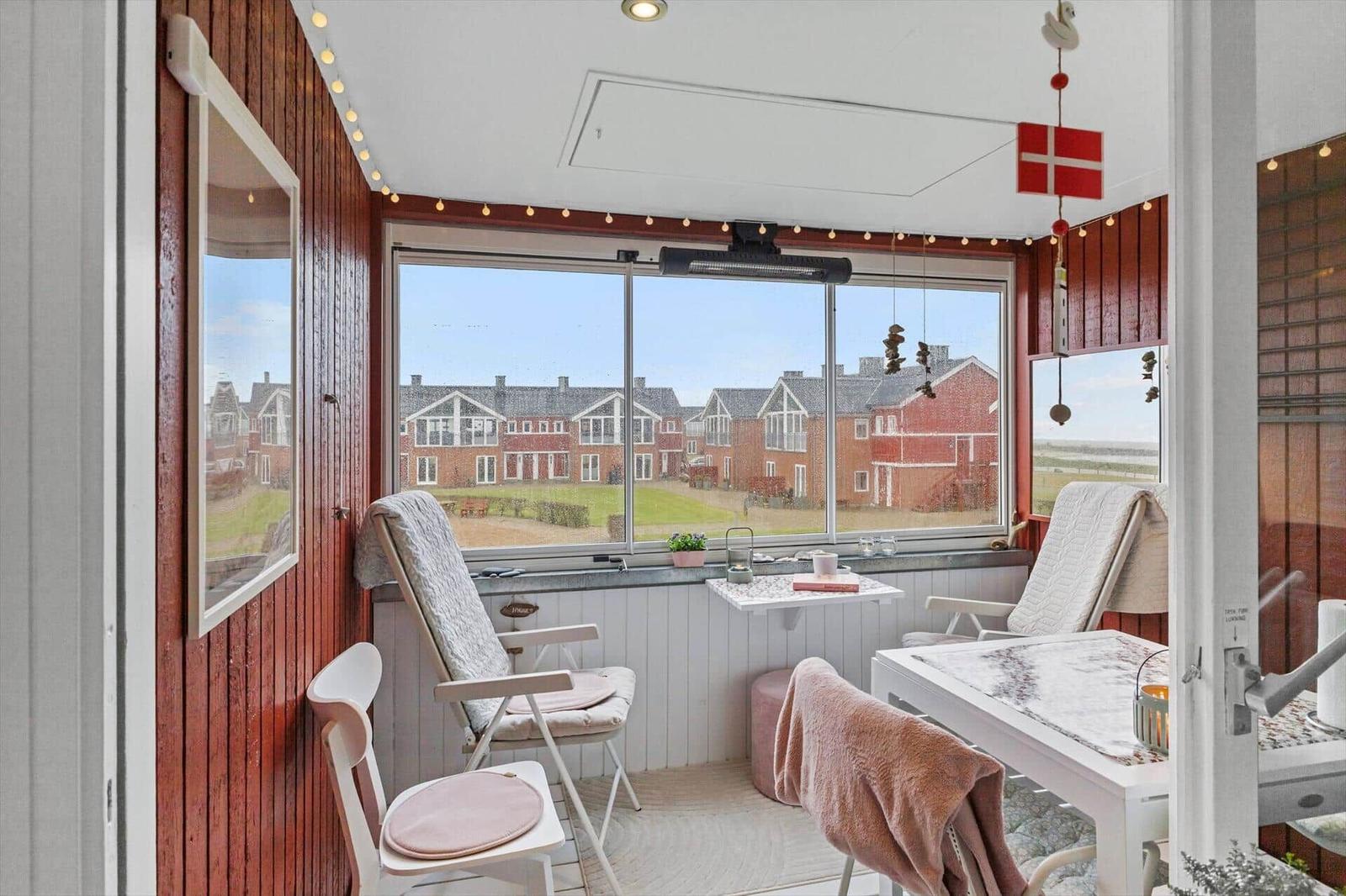 Terrasse mit Sitzgelegenheiten und Blick auf rote Häuser.