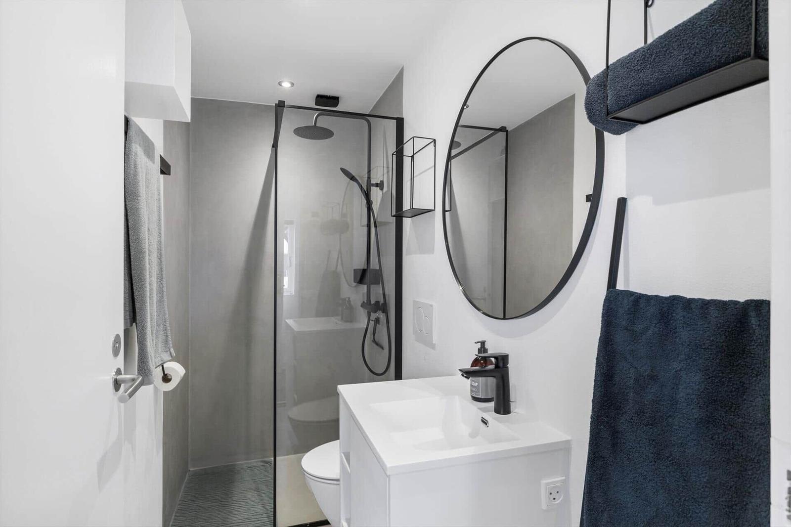 Badezimmer mit Dusche, Waschbecken und Spiegel