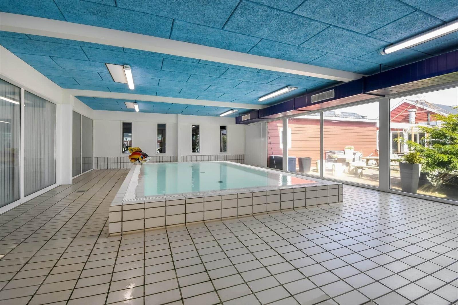 Innenpool mit blauem Deckenverkleidung und großem Glasbereich.