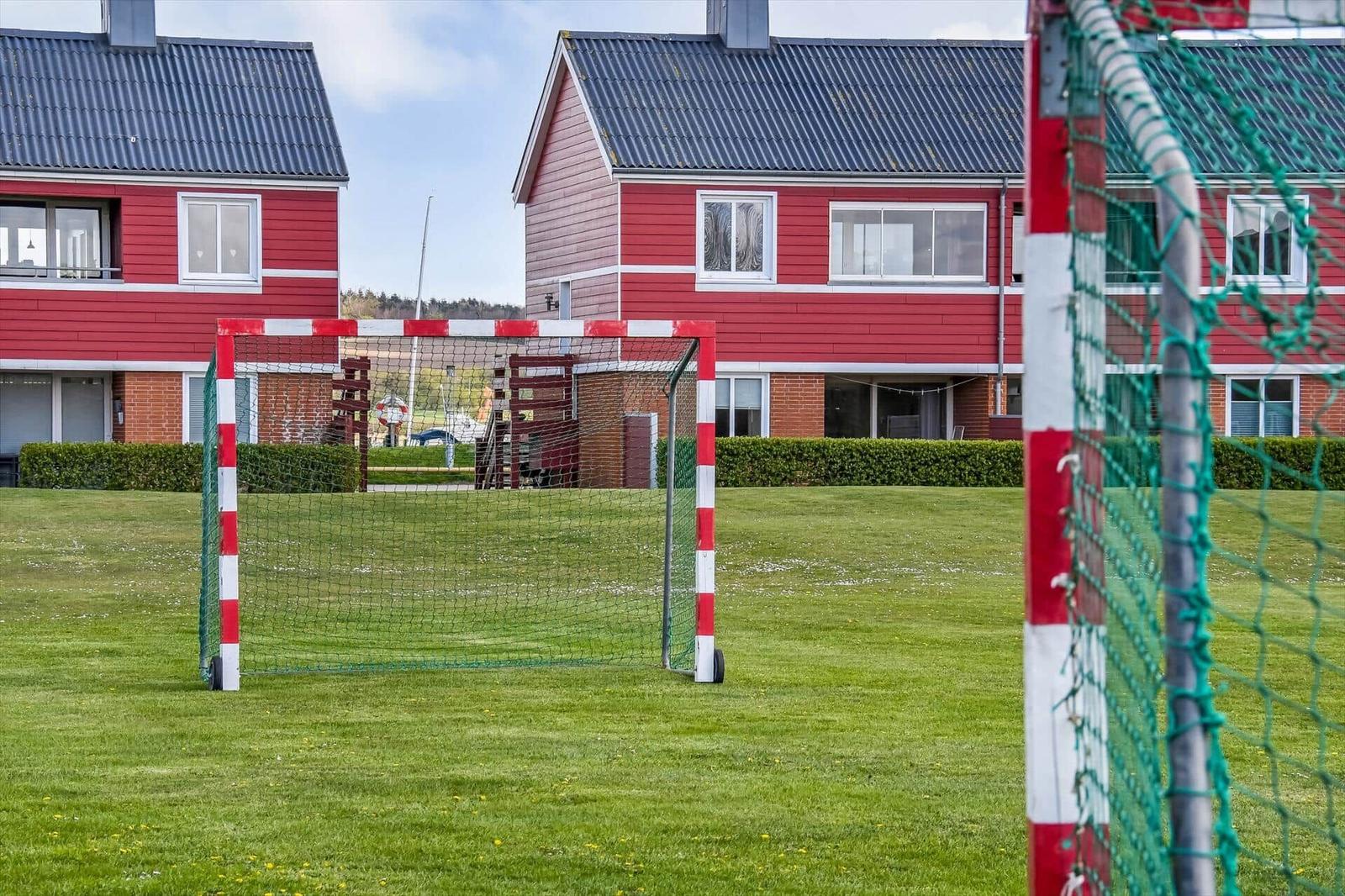Fussballtor auf grünem Rasen vor roten Ferienhäusern