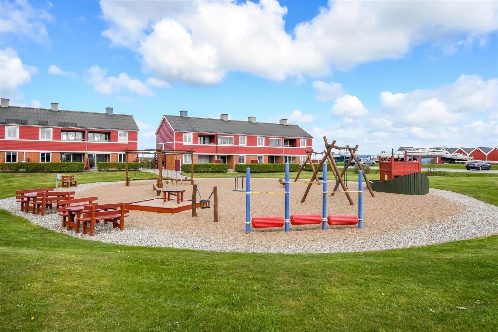 Roter Ferienhauskomplex mit Spielplatz und Grillplatz im Freien.