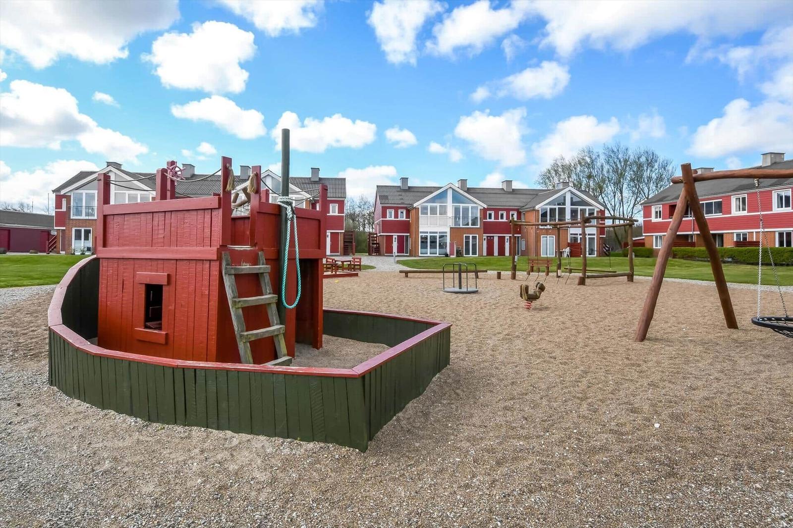 Kinderbereich mit Schiffsspielzeug und Schaukeln vor Wohnhäusern.