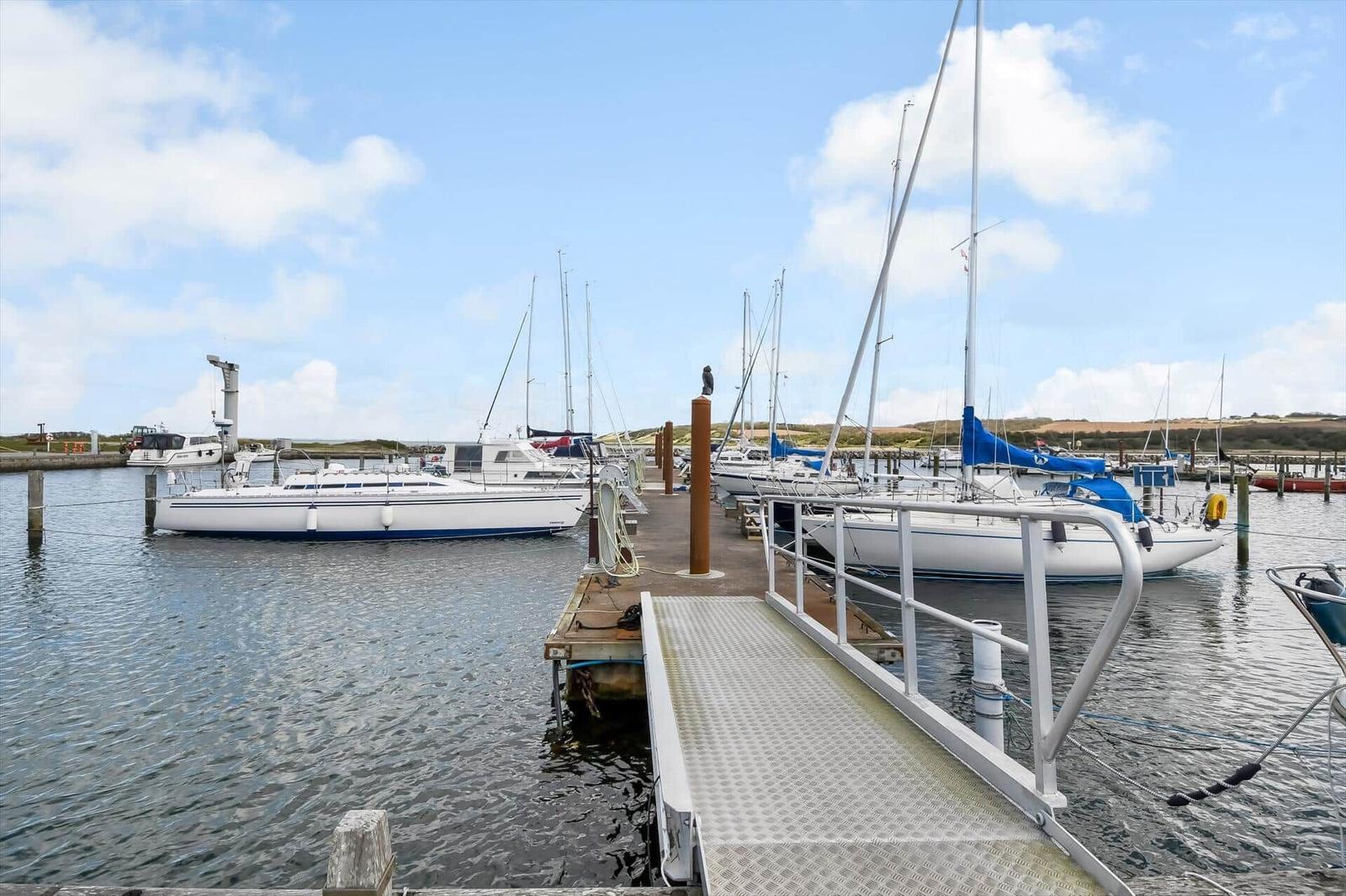Hafen mit Segelbooten und Steg zum Wasser.