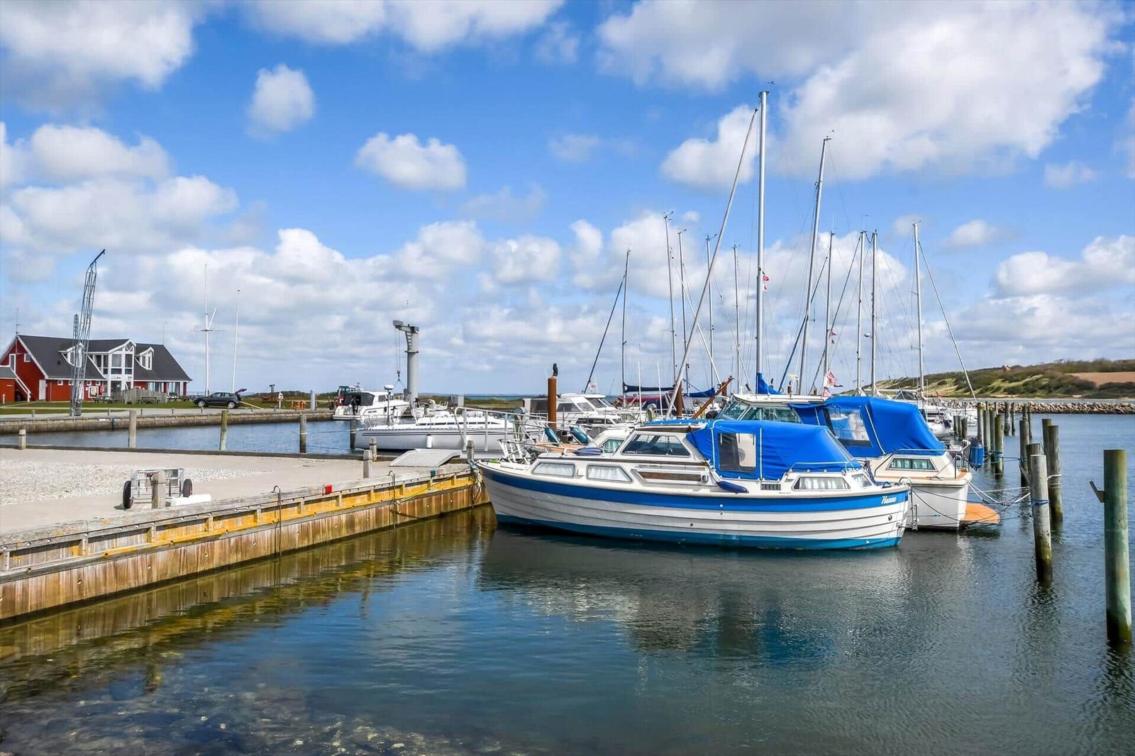 Boote liegen im Hafen, ein rotes Haus ist im Hintergrund sichtbar.
