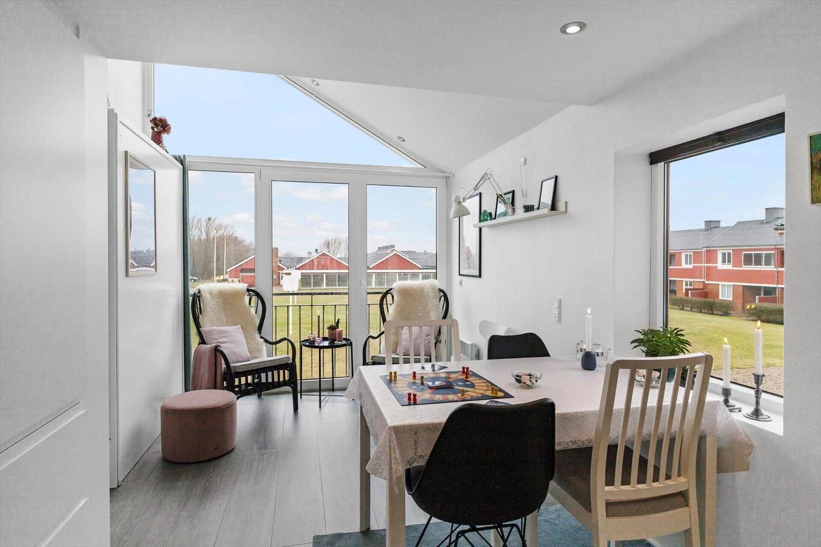 Esszimmer mit Tisch, Stühlen und Blick auf Balkon und Garten.