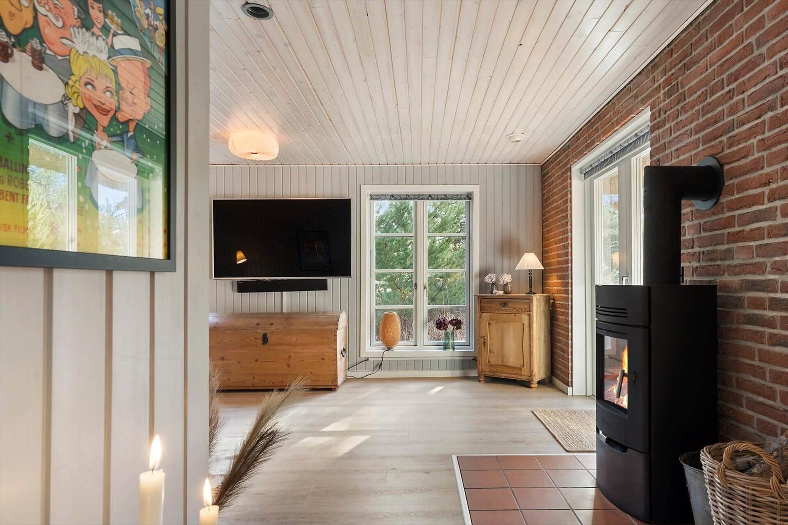Wohnraum mit Kamin, TV und Fenster zum Garten