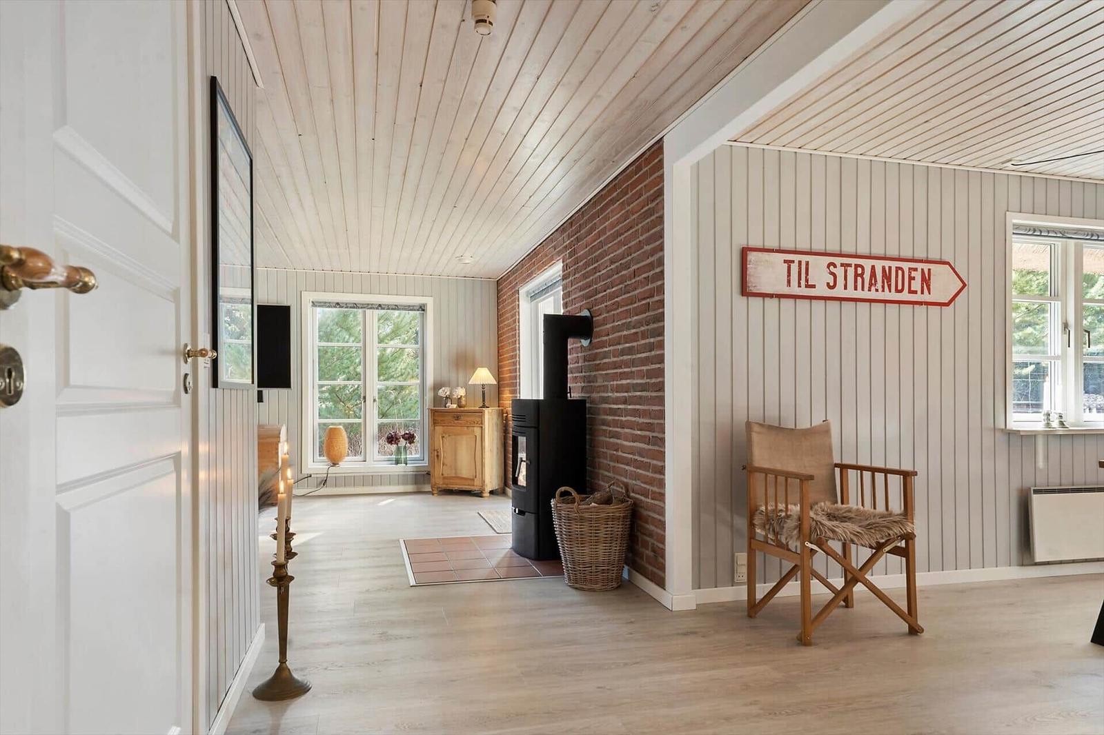 Haus mit Holzdecke, Backsteinwand und Schild zur Strandseite.