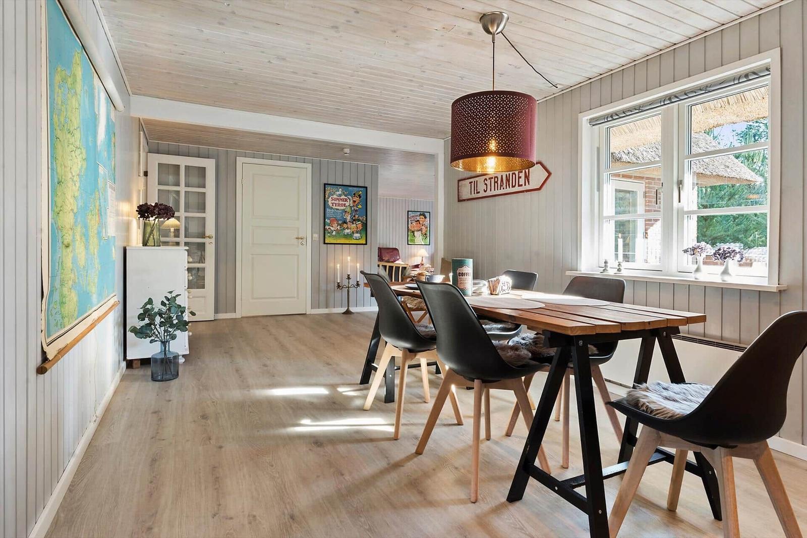Essbereich mit Holztisch, schwarzen Stühlen und Fensterblick auf Strand