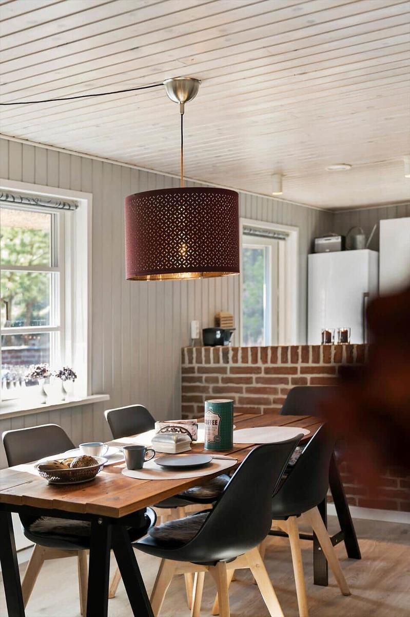Essbereich mit Holztisch, schwarzen Stühlen und hängender Lampe.