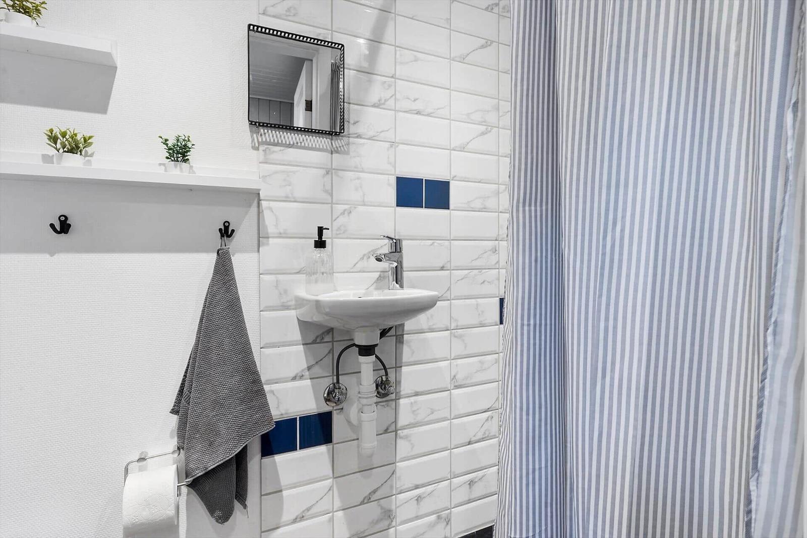 Badezimmer mit Waschbecken, Spiegel und Duschvorhang.