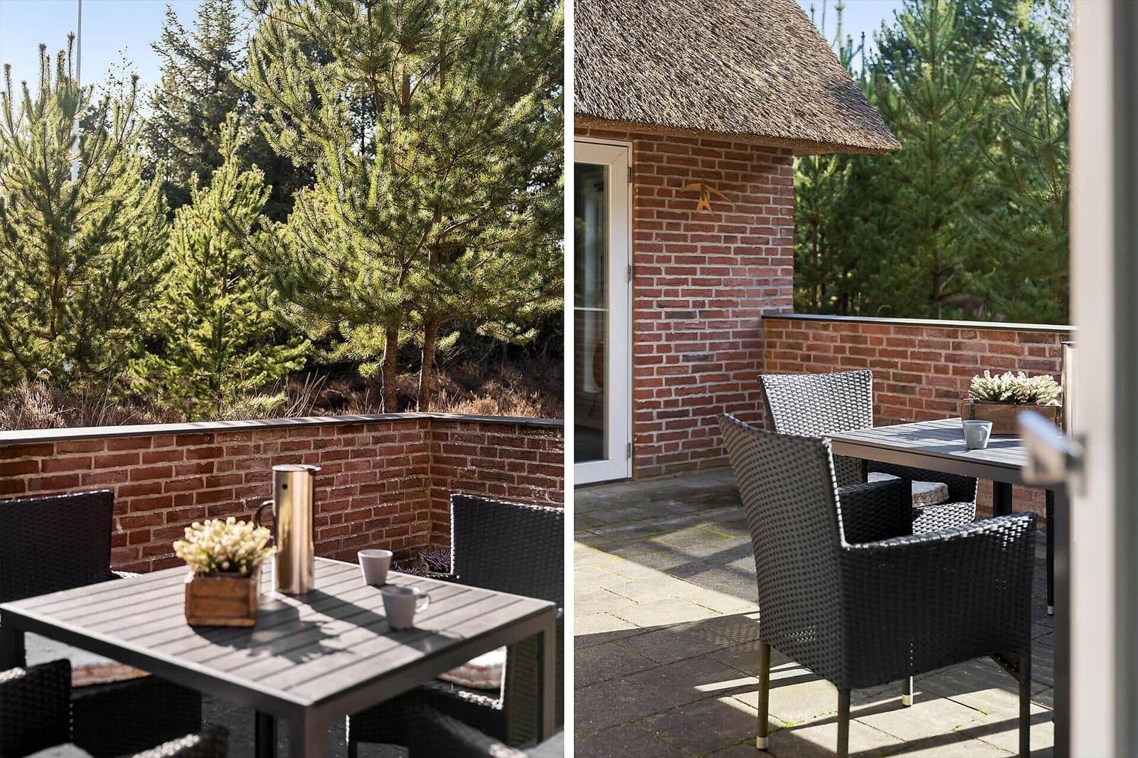 Terrasse mit Tisch und Stühlen, Blick auf Nadelbäume und Backsteinmauer.