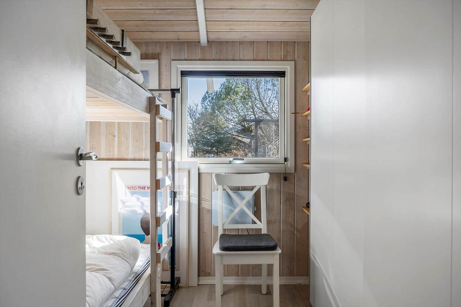 Bedroom with bunk bed, chair, and window with view.