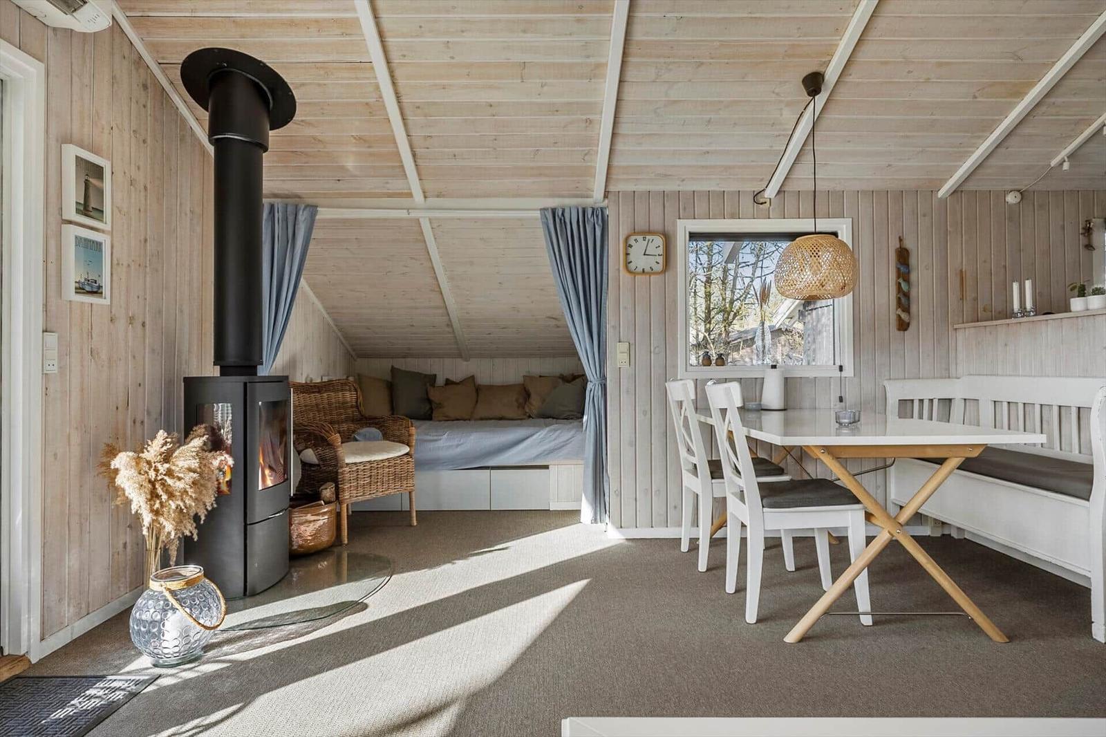 Living area with fireplace, sleeping area, and dining table. Wooden walls and ceiling.