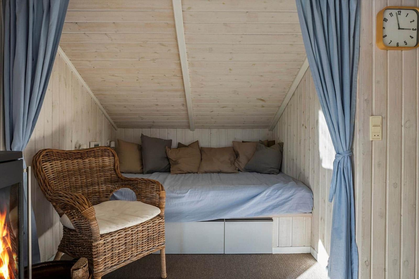 A bedroom with bed, pillows, chair, and fireplace.