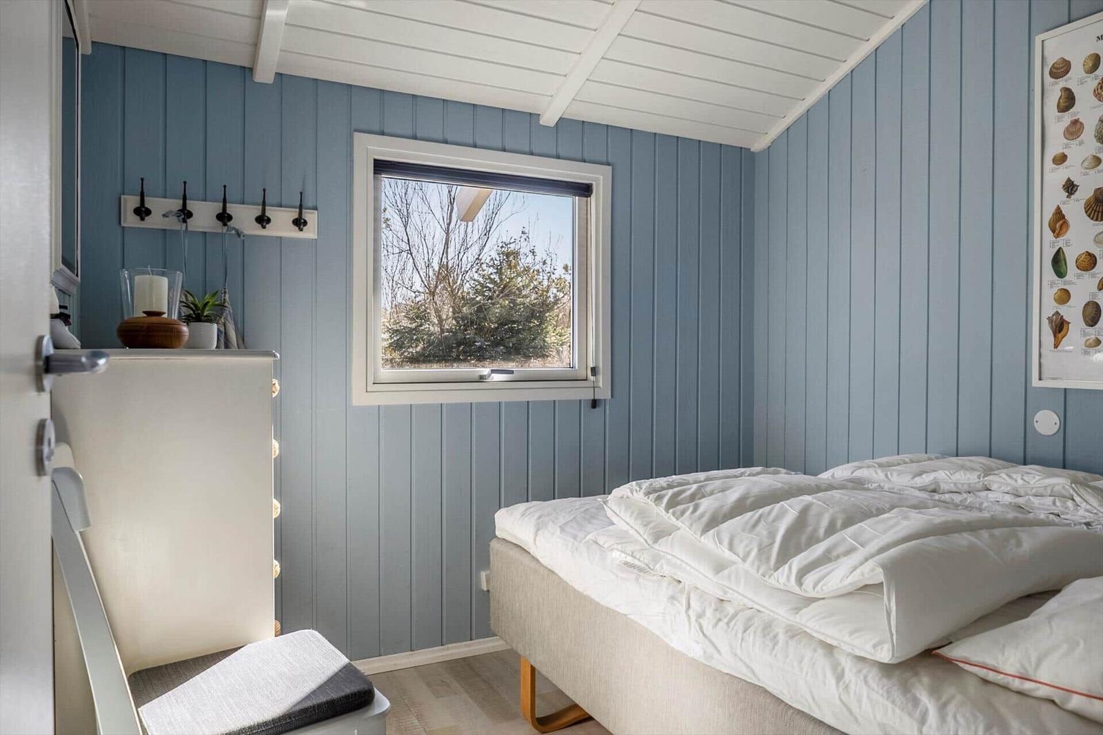Bedroom with bed, window, and wood paneling.