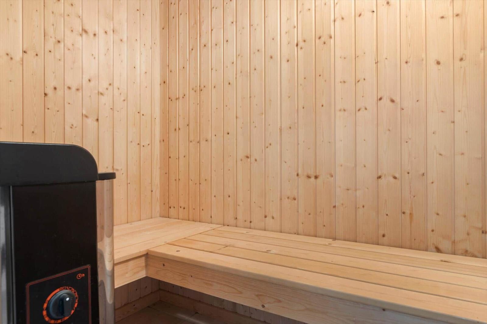 Sauna with wooden walls and bench. Heater on the left.
