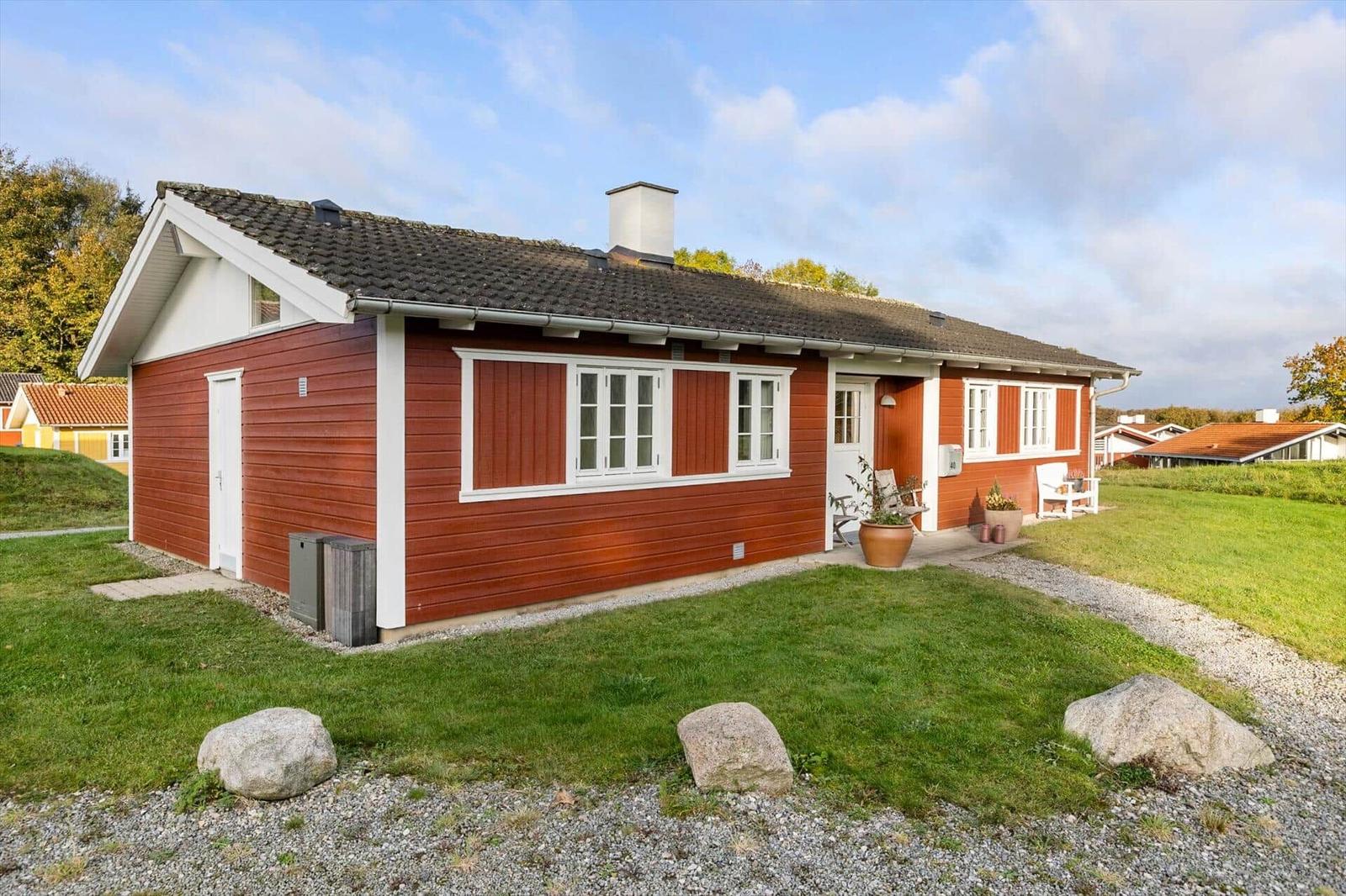 Red wooden house with white window frames and garden
