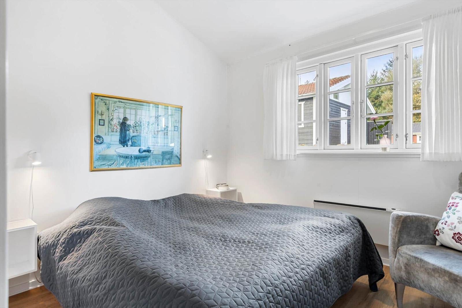 Bedroom with bed, window, and painting on the wall.